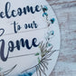 Welcome to Our Home Door Hanger, Birch Wood Round Decor, Rustic Home Accent with Navy Blue Detailing