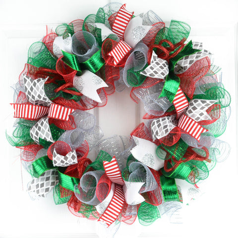 Red silver and green mesh Christmas wreath hanging on white door