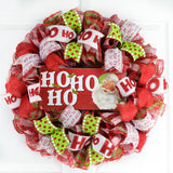 Red White and Lime Green Mesh Wreath with a wooden Ho Ho Ho sign with a Santa Face on the sign, all hanging on a white door
