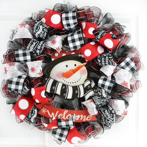Snowma Wreath hanging on white door, with red black and white mesh and ribbons with polka dot, plaid and other designs
